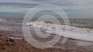 Slow motion of sea waves washing northern sandy beach with water and foam. Camera moves along stormy ocean coastline in