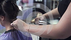 Slow-motion shooting close-up steadikam hairdresser stylist levels the client`s dry hair with a curling iron, combs a