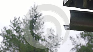 Slow motion shot a drop of water flying from a system of gutters on the roof of a house against the sky 100fps to 25fps 1080p colo