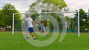 Slow motion shot of family playing soccer in park together. Happy parents and kids playing with ball in green meadow