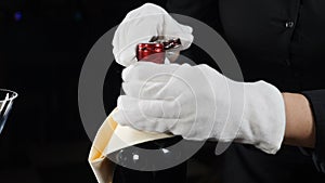 Slow-motion shot of hands of bartender twisting wine knife opening bottle. Shot on black background. Full hd