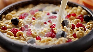 Slow motion shot of pouring milk from the bottle to ceramic bowl with cereals