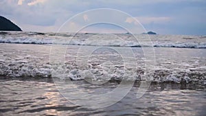 Slow motion shot of seawaves rolling towards the shore during sunset.