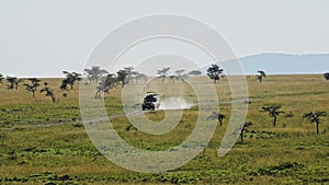 Slow Motion Shot of Vehicle driving adventure leaving a trail of dust, from far away, African Wildli