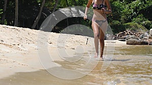 Slow motion shot of young carefree woman in bikini running in the water at beach