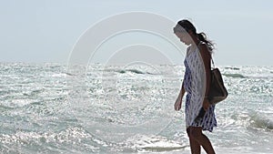 Slow motion shot of a young pregnant Asian woman walking on the beach.