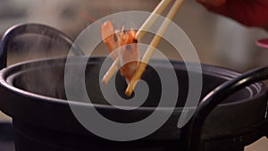 Slow motion shrimp and seafood in chopsticks on hot steam smoke water from hot pot for cooking in party