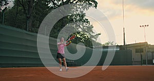 Slow-motion side view of a young athlete trains the serve of the tennis ball. A teenage athlete is playing tennis on a