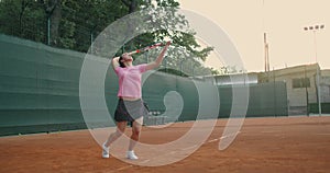 Slow-motion side view of a young athlete trains the serve of the tennis ball. A teenage athlete is playing tennis on a