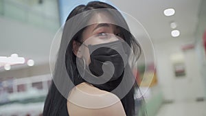 SLOW MOTION smile under face mask of Young attractive Asian woman While walking inside grocery supermarket store during covid-19 c