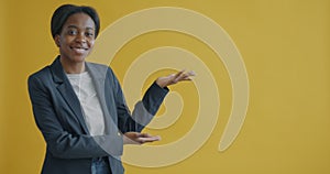Slow motion of smiling young businesswoman pointing sidewards recommending and looking at camera