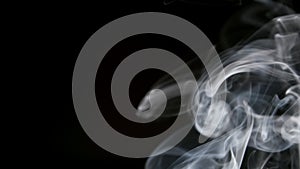 SLOW MOTION: Smoke slowly lifts up on a black background right