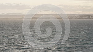 Slow motion stormy mediterranean sea with cloudy weather and soft light with cote d azur airport on background