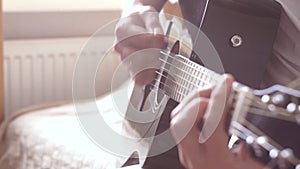 Slow motion of strumming acoustic guitar. Man`s hands and guitar fretboard