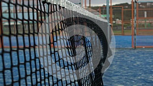 Slow motion of a tennis ball hitting into the net on the blue court outdoors