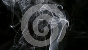 SLOW MOTION: Thin cigarette smoke on a black background