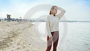 Slow motion of tired young woman taking a break while running on the sandy sea beach. Concept of healthy lifestyle, fitness and