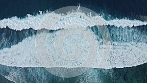 Slow-motion top down aerial view of the ocean giant waves, foaming and splashing