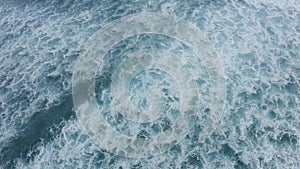 Slow-motion top down aerial view of the ocean giant waves, foaming and splashing