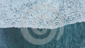 Slow-motion top down aerial view of the ocean giant waves, foaming and splashing