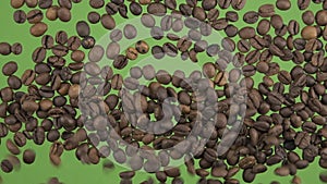 Slow motion. Top view on flying and falling coffee beans. The seeds fall and fill the green screen. Top view