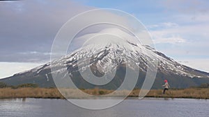 Slow motion - traveler wlking to the view looking to the taranaki volcano in the north island of new zealand and with