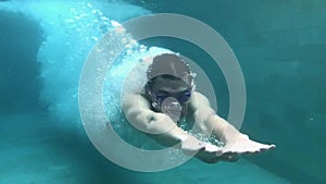 SLOW MOTION. Underwater view of professional male swimmer diving into blue water