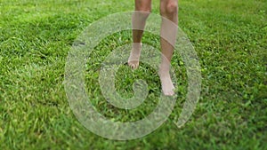 Slow motion unknown girl running barefoot on green meadow at summertime