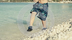 Slow motion video of a baby boy running along the ocean.