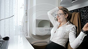 Slow motion video of cheerful businesswoman throwing papers in office and relaxing in chair