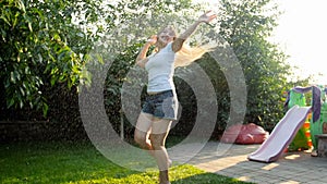 Slow motion video of cheerful young woman dancing and enjoying summer rain at sunset