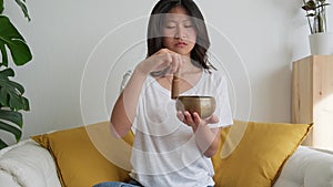 Slow motion video of Chinese young woman playing tibetan singing bowl. 4k resolution.