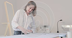 Slow motion video of the fashion designer works at a table with curves and a pattern, she are cutting fabric, around