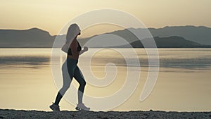 Slow motion video of a girl in a sports suit on a morning jog by the ocean.