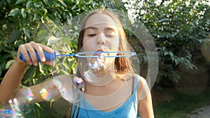 Slow motion video of happy smiling bruntte girl blowing soap bubbles in park at sunny day