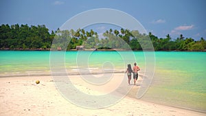 Slow motion video: Interracial happy couple enjoy honeymoon on the tropical beach at sunny summer day.