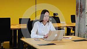 Slow motion video. Pretty Caucasian Businesswoman is sitting on her working desktop, and talking with a colleague