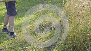 Slow motion video of senior farmer using scythe to mow the lawn traditionally.