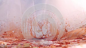 Slow-motion view of a falling and breaking glass bottle filled with red liquid