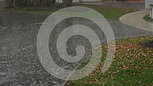 Slow Motion view, heavy rain water drops falling into big puddle on asphalt, flooding the street.