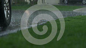 Slow Motion view, heavy rain water drops falling into big puddle on asphalt, flooding the street on suburb. Close up