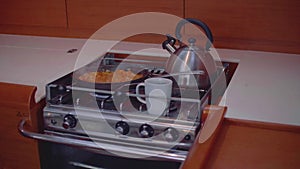 Slow motion view of kettle and cups with tea and coffee on cooker hanging on cardan and swaying because of motion