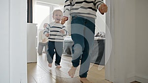 Slow-motion view of a two little boy's running down the long wooden corridor at home.