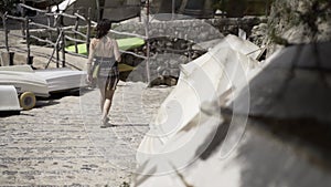 Slow motion view of a young European girl walking down some stone stairs in the sunlight.