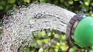 Slow motion watering can sprays water on plants