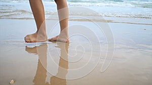 Slow motion woman feet walking on the sand beach with nature sea wave coast for summer vacation concept