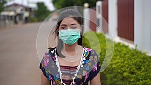 Slow-motion of woman in medical masksurgical mask walking outside a home, coronavirus protection