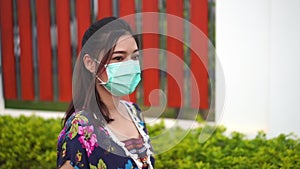 Slow-motion of woman in medical masksurgical mask walking outside a home, coronavirus protection