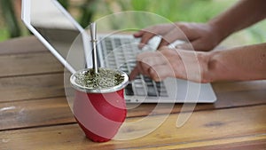 Slow Motion. Woman working on laptop and drinking yerba mate tea in home office