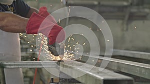 Slow motion of a worker using metal grinder with sparks flying at a metal shop